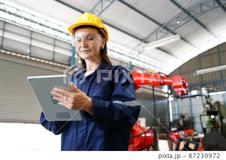 Female industrial worker working with manufacturing equipment in a factory Female industrial worker working with manufacturing equipment in a factory 87230972