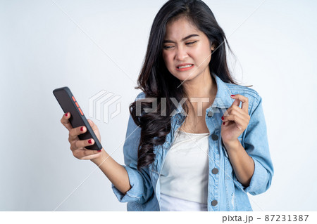 asian woman shocked while using mobile phone asian woman shocked while using mobile phone 87231387