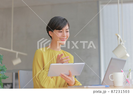 オンラインミーティング_タブレットを持ち話す女性1 オンラインミーティング_タブレットを持ち話す女性1 87231503
