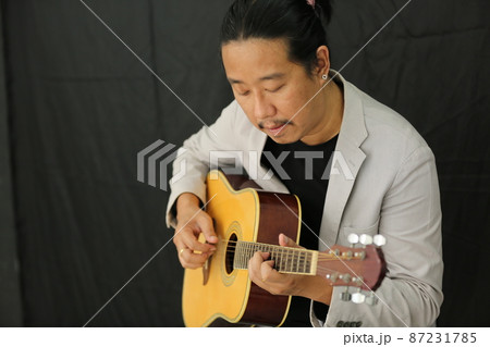 Portrait of men musician playing guitar in studio. Portrait of men musician playing guitar in studio. 87231785