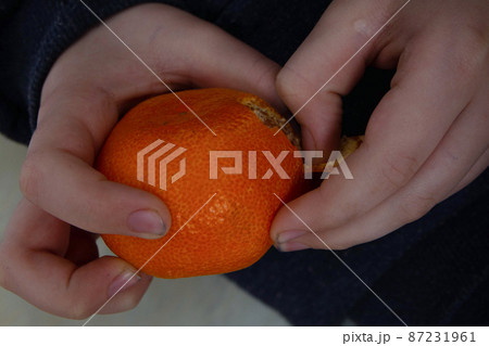 a child with dirty hands cleans a tangerine to eat it a child with dirty hands cleans a tangerine to eat it 87231961