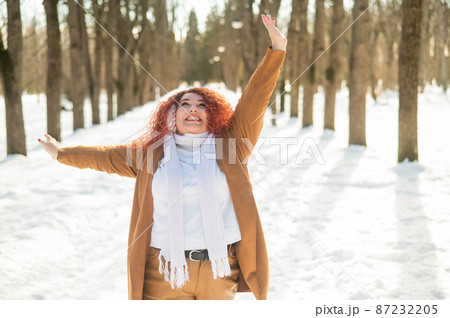 A fat woman listens to music with headphones and dances in the park in winter. A fat woman listens to music with headphones and dances in the park in winter. 87232205