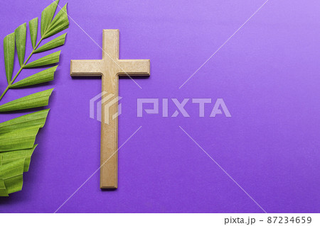 Cross and palm leaves on purple background. Lent season concept. 87234659