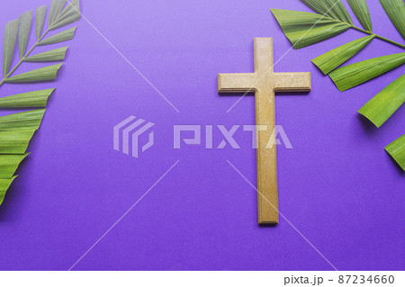 Cross and palm leaves on purple background. Lent season concept. 87234660