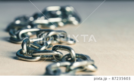 Metal iron chain slowly falls on a wooden table 87235603