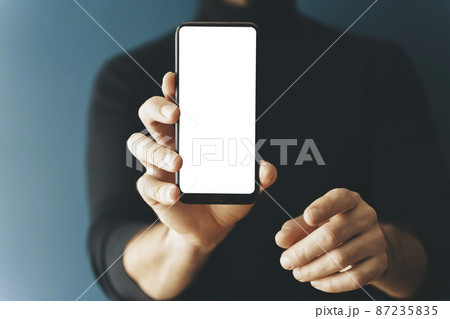 Smartphone blank screen presentation. A young man is holding a phone with a white empty screen mockup. Internet, applications, business, technology concept. Smartphone blank screen presentation. A young man is holding a phone with a white empty screen mockup. Internet, applications, business, technology concept. 87235835