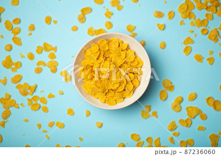 Cereal cornflakes for breakfast in a pink bowl on a blue background. Minimal art creative food concept 87236060