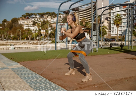 Young attractive woman stretching exercising equipment outdoors 87237177