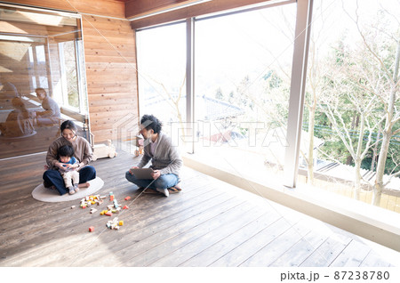 木造のきれいな新築の広い部屋で美人なママと家族団らんの幸せな若いファミリー　右にコピースペースあり　 87238780