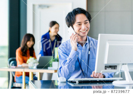 オフィスで電話する若いエンジニアの男性 オフィスで電話する若いエンジニアの男性 87239677