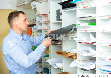 Office worker puts paper and printing film on the shelves Office worker puts paper and printing film on the shelves 87243581