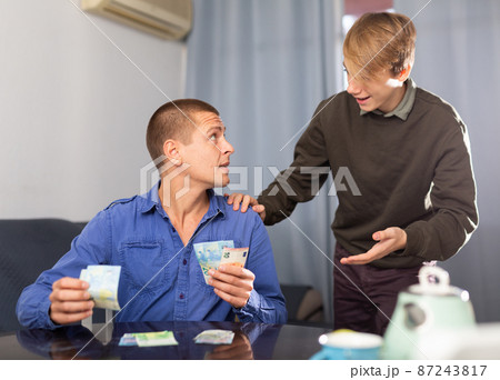 Father giving his teenage son pocket money Father giving his teenage son pocket money 87243817