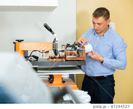 Man printing on coffee mugs in workshop 87244527