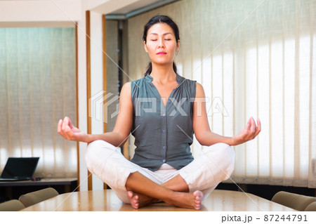 Businesswoman sitting at the table in lotus position 87244791