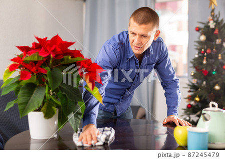 Man cleaning table with rag at home before christmas Man cleaning table with rag at home before christmas 87245479