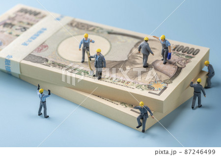 お金（札束）とミニチュアの作業員 87246499