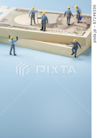 お金（札束）とミニチュアの作業員 87246500