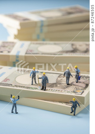 お金（札束）とミニチュアの作業員 87246505