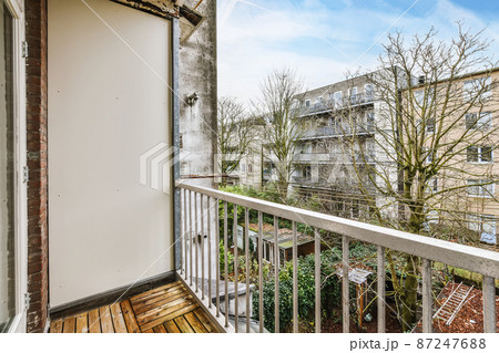 Charming design of a long balcony with iron handrails and a view of a residential building Charming design of a long balcony with iron handrails and a view of a residential building 87247688