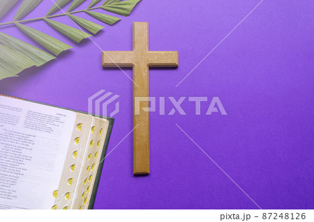 Cross and holy bible with palm leaves on purple background. Holy week concept. 87248126