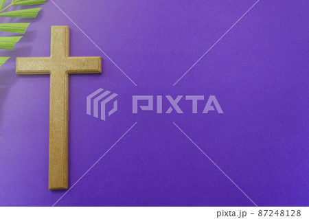 Cross and palm leaves on purple background. Lent season concept. Cross and palm leaves on purple background. Lent season concept. 87248128