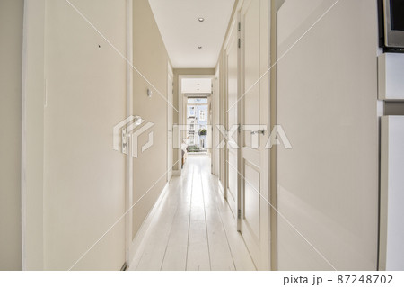 Long narrow corridors in a modern apartment with white doors Long narrow corridors in a modern apartment with white doors 87248702