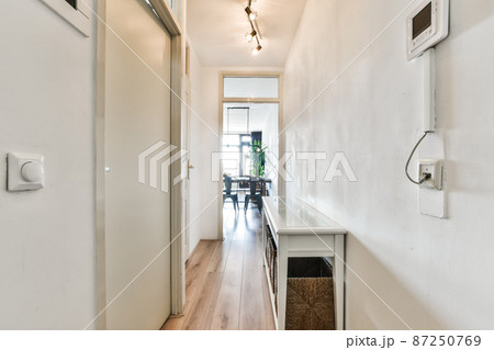 Long narrow corridors in a modern apartment with white doors Long narrow corridors in a modern apartment with white doors 87250769
