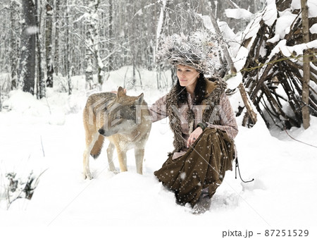 Female forest dweller with a wild wolf in the winter forest Female forest dweller with a wild wolf in the winter forest 87251529