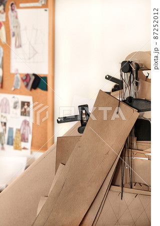 The atmosphere of a creative sewing workshop. Details of patterns. Hangers with patterns for clothes hang on a bracket. Concept: atelier and sewing business, sewing training, hobbies and needlework. The atmosphere of a creative sewing workshop. Details of patterns. Hangers with patterns for clothes hang on a bracket. Concept: atelier and sewing business, sewing training, hobbies and needlework. 87252012