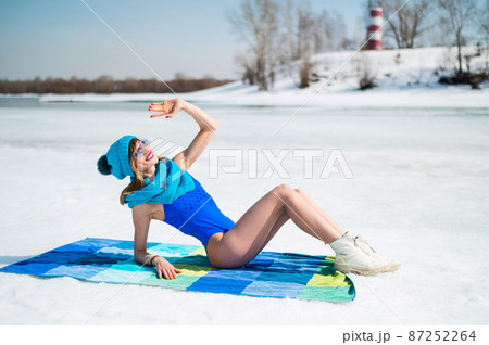 Beautiful caucasian woman in a swimsuit and a hat sunbathes on the snow. Beautiful caucasian woman in a swimsuit and a hat sunbathes on the snow. 87252264