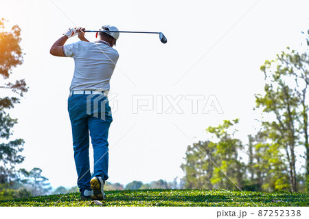 Golfer playing golf in the evening golf course, on sun set evening time. Man playing golf on a golf course in the sun. Golfer playing golf in the evening golf course, on sun set evening time. Man playing golf on a golf course in the sun. 87252338