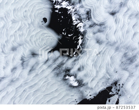 Aerial view of a winter snow-covered pine forest and frozen lake 87253537
