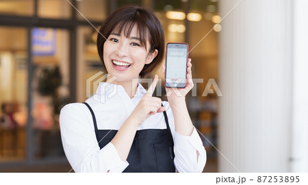 スマホアプリを紹介する女性スタッフ スマホアプリを紹介する女性スタッフ 87253895