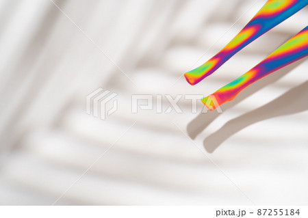 Neon colored doll legs on white background with palm tree shadow Neon colored doll legs on white background with palm tree shadow 87255184