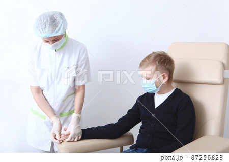 A blood test in a child. A boy in a protective mask is donating blood in a medical laboratory. Blood from the finger.A nurse and a child. The concept of healthcare.Medical laboratory A blood test in a child. A boy in a protective mask is donating blood in a medical laboratory. Blood from the finger.A nurse and a child. The concept of healthcare.Medical laboratory 87256823