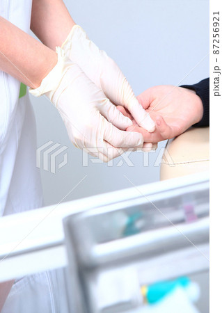 A child gives blood from a finger in a medical laboratory. Blood test. A nurse and a child. The concept of healthcare.Unrecognizable persons.Vertical photo. 87256921