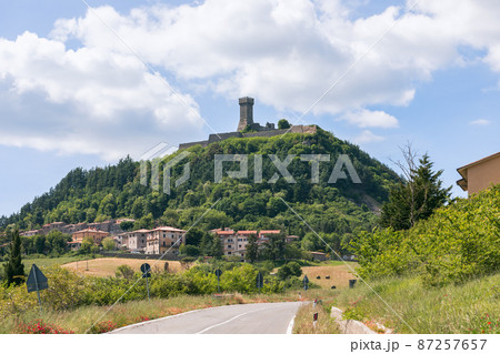 Radicofani town beneath and Fortress (Fortezza di Radicofani) on a basaltic cliff. Tuscany, Italy 87257657