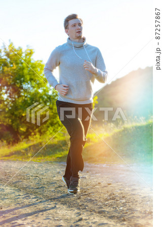 Man jogging in rural nature at beautiful summer day. Sport fitness model caucasian ethnicity training outdoor. Man jogging in rural nature at beautiful summer day. Sport fitness model caucasian ethnicity training outdoor. 87257867