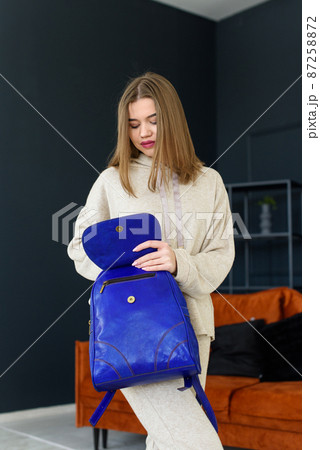 photo of a women in beige sports suit and blue leather backpack posing in a hotel room. selective focus 87258872