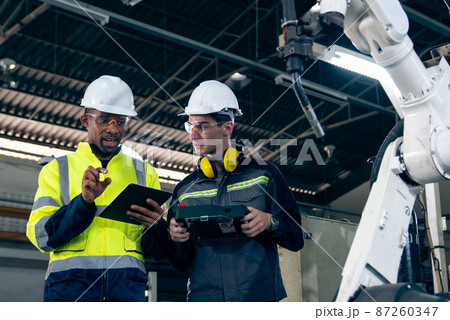 Factory workers working with adept robotic arm in a workshop Factory workers working with adept robotic arm in a workshop 87260347
