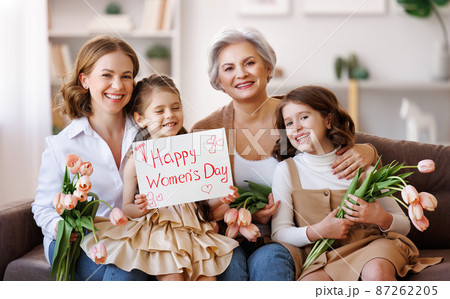 Happy International Womens Day. family grandmother, mother and daughter with flowers and a poster celebrate holiday Happy International Womens Day. family grandmother, mother and daughter with flowers and a poster celebrate holiday 87262205