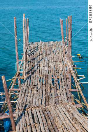 Wooden fishing dock by blue sea 87263394