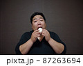 おむすびを食べている太った人 87263694