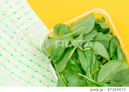 Fresh Baby Spinach Leaves in Transparent Plastic Package on Yellow Background Fresh Baby Spinach Leaves in Transparent Plastic Package on Yellow Background 87264072
