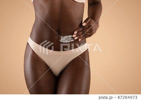 Cropped of dark-skinned woman applying cream on her waist 87264073