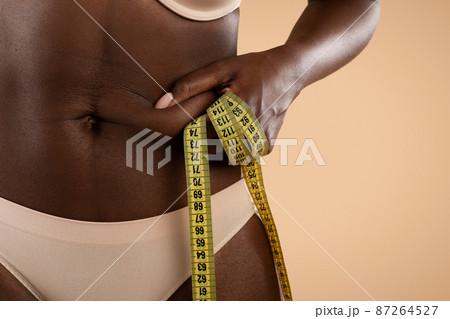 Cropped of black woman in underwear pulling skin on belly 87264527