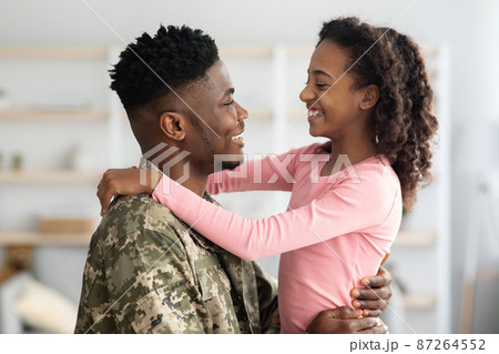 Side view of black father in military uniform hugging child Side view of black father in military uniform hugging child 87264552