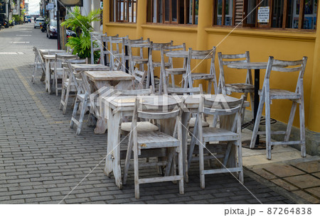 Empty wooden chairs and tables outside the restaurant in the morning, quiet and calm cobblestone Streets in Galle fort. Empty wooden chairs and tables outside the restaurant in the morning, quiet and calm cobblestone Streets in Galle fort. 87264838