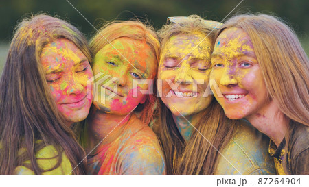 Cheerful girls posing smeared in multi-colored powder. Close-up faces. 87264904