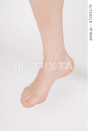 Barefoot and legs isolated on white background. Closeup shot of healthy beautiful female feet. Health and beauty concept. Side view of human foot ream with neutral manicure or pedicure. Sole of foot. 87265170